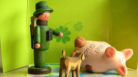 Jäger-Figur mit Hunde-Figur neben liegender großer Schweine-Figur vor grünem Hintergrund